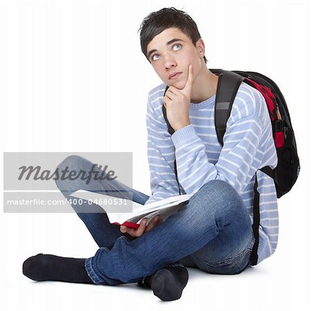 Young contemplative male student sitting on floor with book. Isolated on white.
