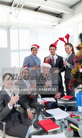 Business people with novelty Christmas hat toasting at a party in the office