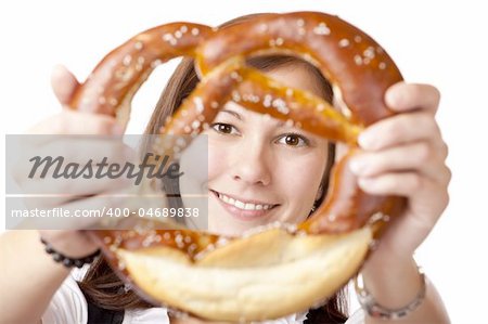 Portrait of young woman in Dirndl cloth looking trough Oktoberfest Pretzel. Isolated on white background.