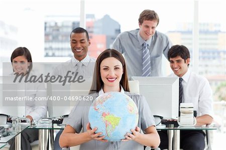 Brunette businesswoman and her team showing a terrestrial globe in the office