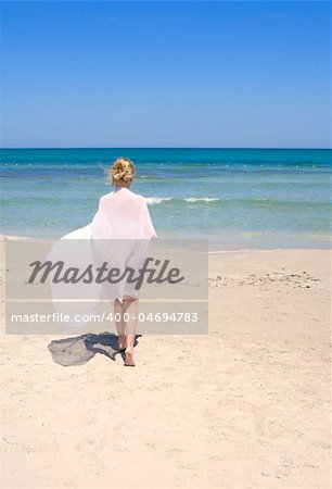 woman on the beach with a white sarong under blue sky