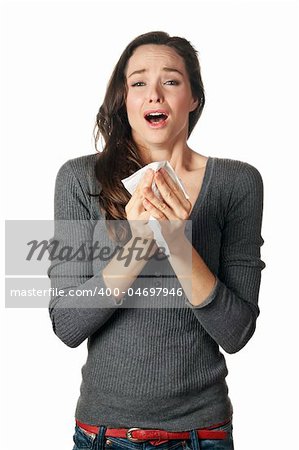 An attractive woman with hay fever or a cold sneezing into tissue