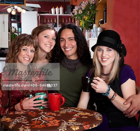 Four smiling friends enjoying coffee in a cafe
