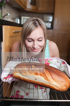 Delighted blond woman baking bread in a kitchen