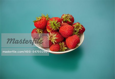 Strawberries in bowl on a blue background