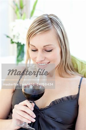 Smiling woman drinking red wine siting on a sofa