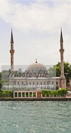 A mosque on the edge of a large river against a blue sky