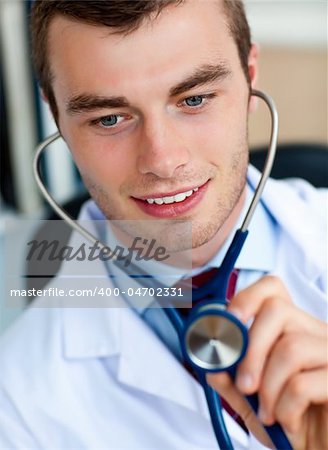 Charming young doctor examining with a stethoscope  in his office