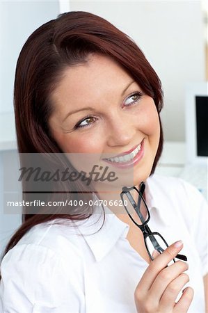 Radiant businesswoman holding glasses sitting in her office