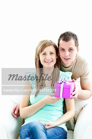 Young boyfriend giving a present to his glowing girlfriend against white background