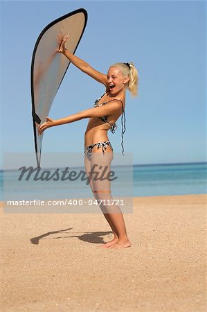 A pretty blonde girl wearing a bikini on the beach. She's playing with a reflector from a photo shoot.