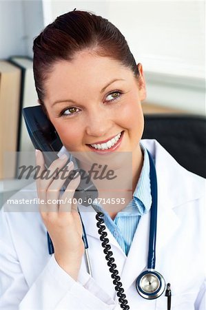 Delighted female doctor talking on phone in her office