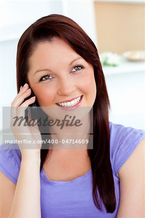 Merry young woman using her cellphone on a sofa at home