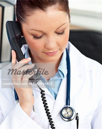 Portrait of a serious female doctor phoning in her office sitting at her desk