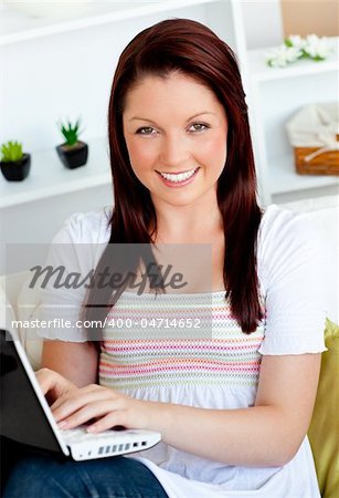 cheerful woman working with her laptop sitting at home smiling at the camera