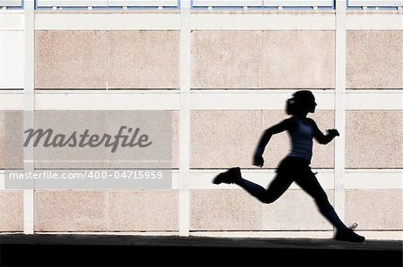 Woman in the shadows of building runs for exercise.