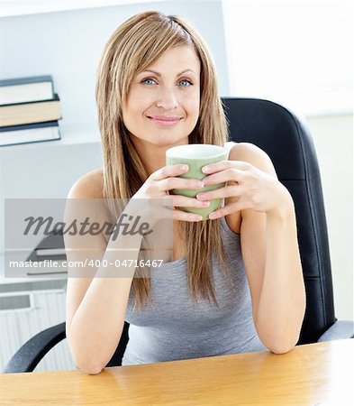 Glowing businesswoman holding a cup at her desk in her office