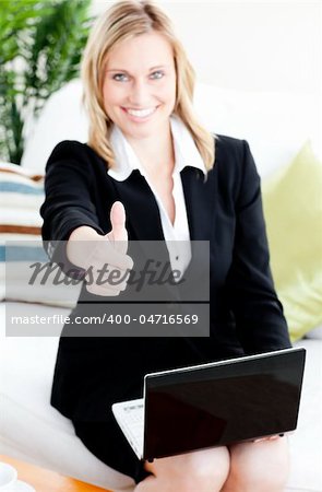 Postive businesswoman with thumb up using her laptop sitting on a sofa