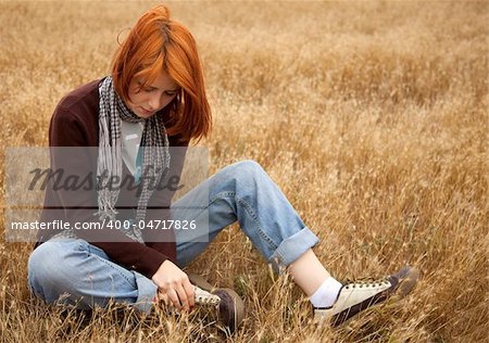 Lonely sad red-haired girl at field