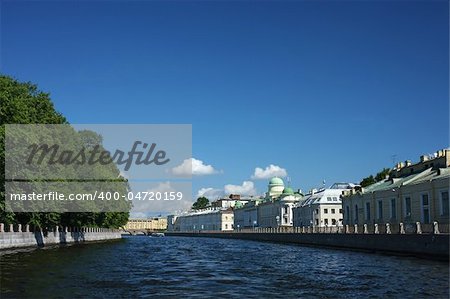 A daylight image of St. Petersburg city channel with a park and some historical buildings