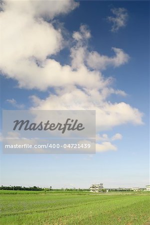 Countryside scenery with buildings under blue sky and white clouds.