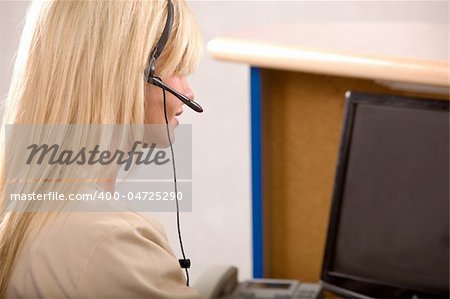 A receptionist working at a computer with a headset