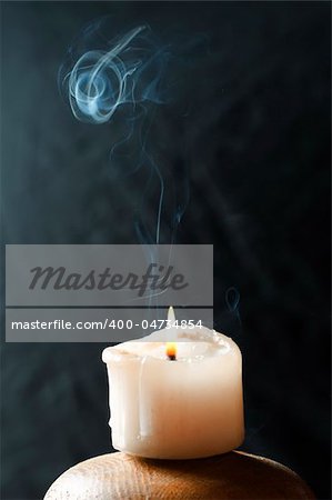 A single candle, with  beautiful smoke trail coming from it