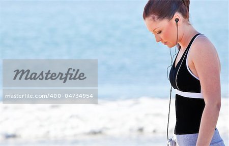 Athletic woman listening music on the beach