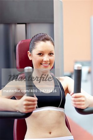 beautiful athletic woman using a bench press smiling at the camera in a fitness center