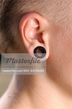 A big aperture piercing in the ear of a teenager