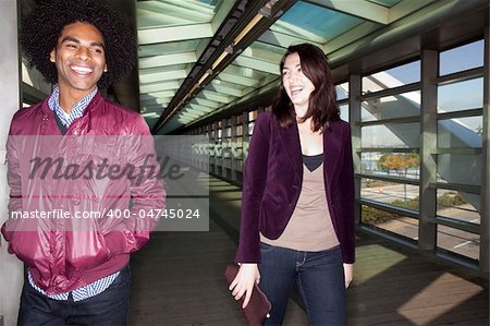 Two young people walking and joking in an urban setting - sharp focus on male