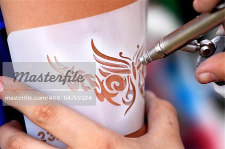 creating an air brush tattoo on a young girl's arm