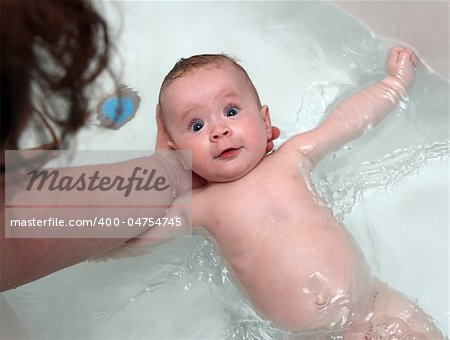 happy baby girl bath by mother in bathtub