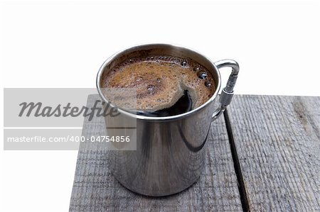 Metal mug of coffee on the wooden table. Isolated on white background.