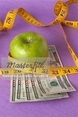 An apple, tape measure, and American currency represents the concept of measuring the cost of healthcare, food, or education.  Can also work for concept of the cost of healthcare, education or food.