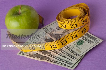 An apple, tape measure, and American currency represents the concept of measuring the cost of healthcare, food, or education.  Can also work for concept of the cost of healthcare, education or food.