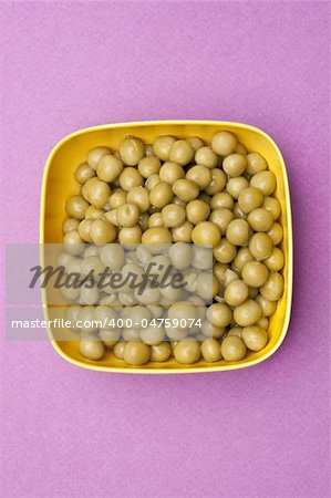 Bowl of Canned Peas on a Vibrant Purple Background.