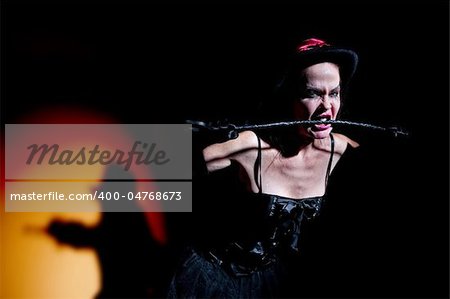 Pale looking woman dressed in black with whip