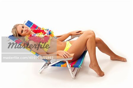 Young woman with yellow bikini and red lei lying in beach chair