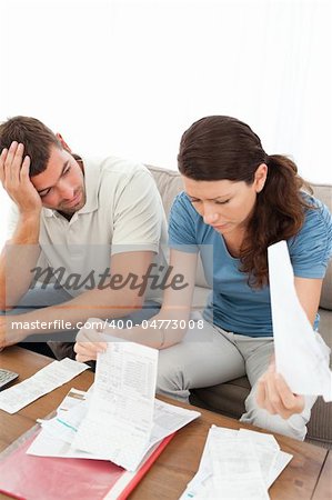 Stressed man and woman looking at their bills in the living room at home