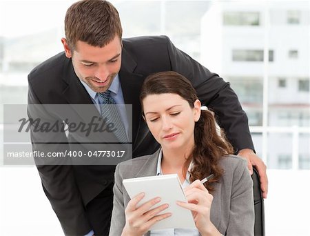 Happy businessman helping a businesswoman working at her desk in the office