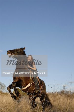 rearing black stallion and happy young woman in a field