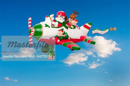 Santa Claus flying his airplane with Happy Holidays banner in the sky with his elves and Rudolf the Red nosed Reindeer.