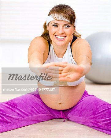 Smiling beautiful pregnant woman doing stretching exercises