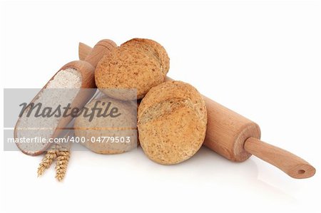 Bread roll stack with wholegrain flour in a scoop and wooden rolling pin with loose wheat, over white background.