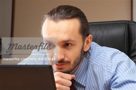 Businessman at his workplace look in laptop.