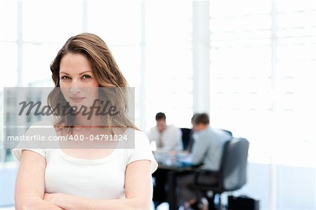 Beautiful businesswoman standing in front of her team while working in the background