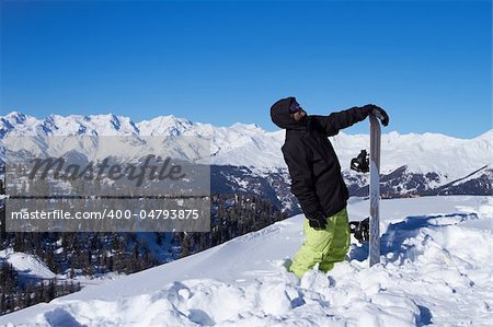 Male snowboarder standing in snow and looking up