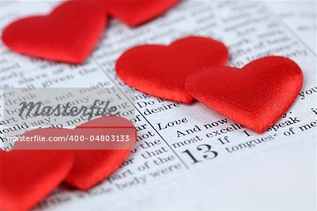 Bible open to 1st Corinthians 13, a passage about love, and little heart shaped confetti. Shallow dof