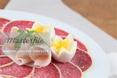 Salami with parmesan crust on a plate with ham and eggs. Shallow dof